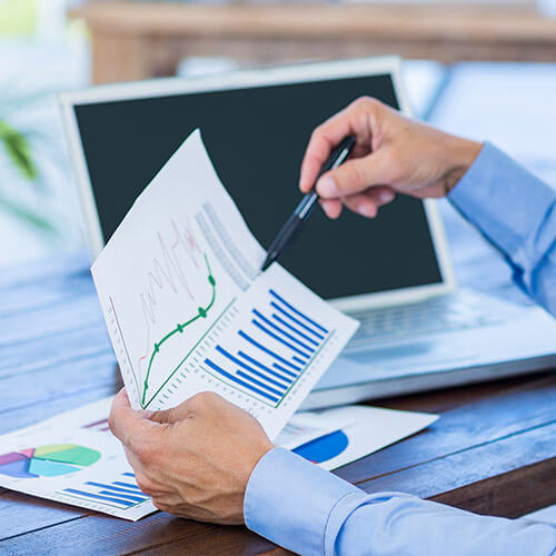 Colaborador de Maverick Border Services en escritorio con laptop y documentos estadísticos, efectuando servicio de trade consulting